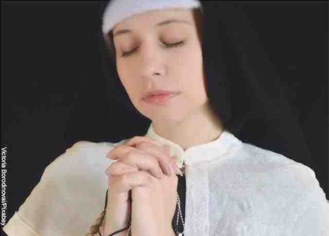 Foto di una suora che prega con una camandula